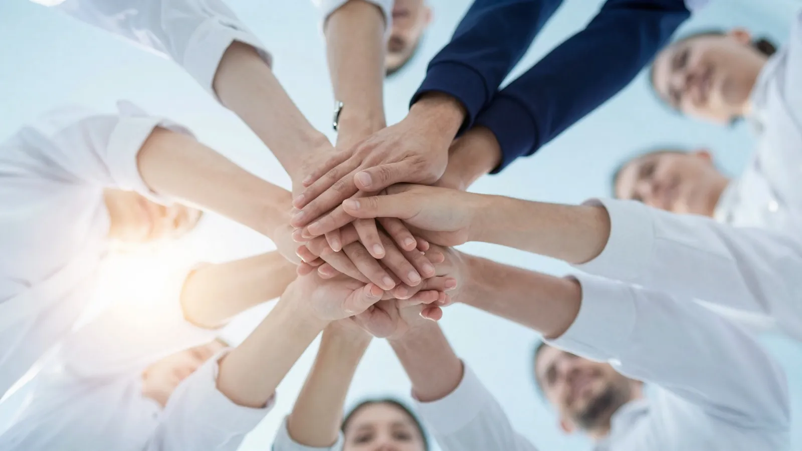 Equipo de Bilog uniendo las manos en señal de trabajo conjunto